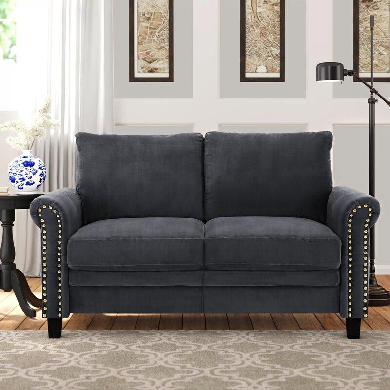Sofá loveseat Fuka de Hanabi Living en tela gris con cojines decorativos y estructura moderna en una sala elegante.